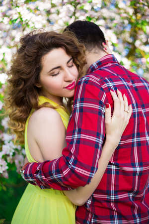 portrait of happy beautiful girl embracing her boyfriend in blooming summer gardenの写真素材