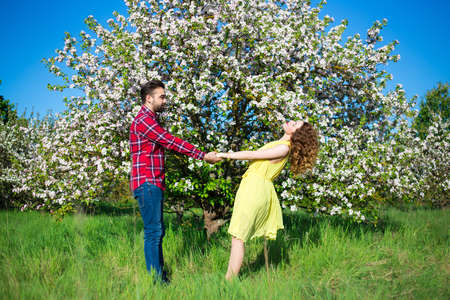 young beautiful couple walking in blooming summer gardenの写真素材