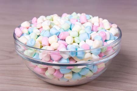 colorful mini marshmallows in glass bowl on wooden tableの写真素材