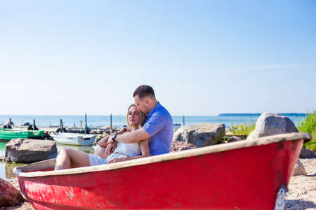 beautiful couple sitting in old boat on summer beachの写真素材