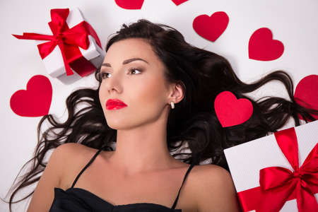 portrait of young woman with gift boxes and paper hearts isolated on white backgroundの写真素材
