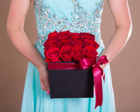 close up of black box with red rose flowers in female handsの写真素材