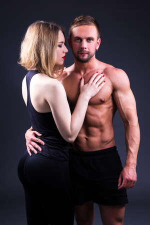 love and sport concept - sexy woman and muscular man over grey backgroundの写真素材
