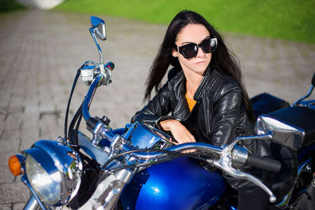 portrait of young beautiful woman sitting on retro motorbikeの写真素材