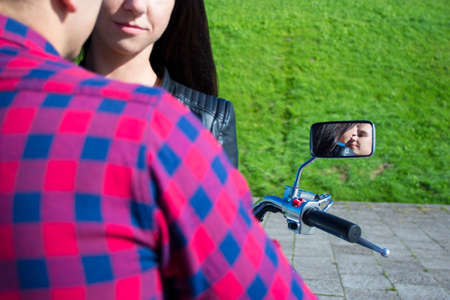 reflection of young kissing couple in motorbike mirrorの写真素材