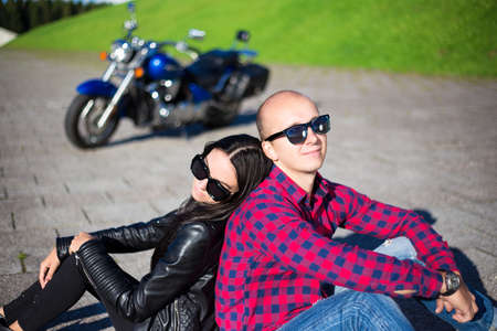 travel concept - young couple in love sitting on the road with retro motorbikeの写真素材