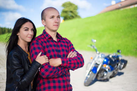 young beautiful couple posing on road with retro motorcycleの写真素材