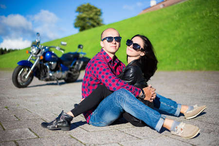 happy young beautiful couple sitting on the road with retro motorbikeの写真素材