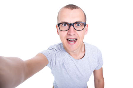 funny young man in glasses with braces on teeth taking selfie photo isolated on white background