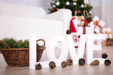 wooden letters "love" and pine cones in decorated christmas interiorの写真素材