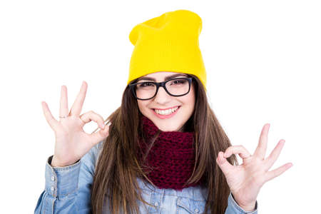 portrait of young woman in winter clothes showing ok sign isolated on white backgroundの写真素材