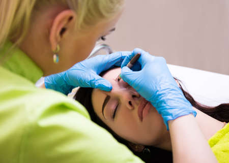 permanent eyebrow make up - close up of cosmetician preparing a woman for procedure