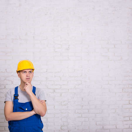 builder in uniform and copy space over white brick wall