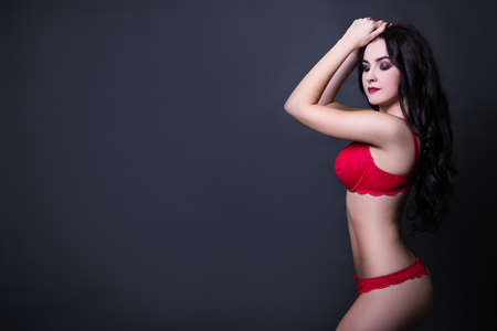 side view of beautiful sexy woman in red lace lingerie posing over black background with copy spaceの写真素材