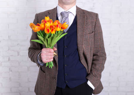 Women's or mother's day concept - close up of flowers in male hands over white backgroundの写真素材