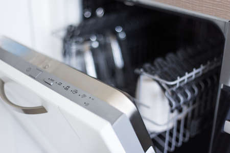 close up of open dishwasher with clean utensils in kitchenの写真素材