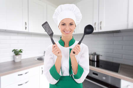 young cheerful chef woman in uniform with tools in modern kitchen