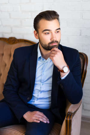 business, richness and success concept - portrait of young handsome man sitting on vintage sofaの写真素材