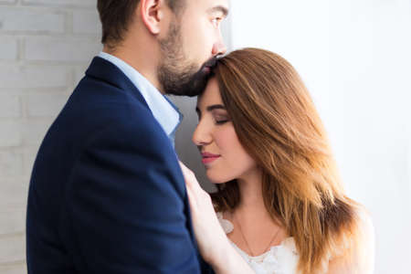 love concept - close up portrait of young beautiful couple embracing at homeの写真素材