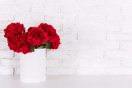 red flowers in vase in the table over white brick wallの写真素材