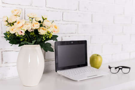 rose flowers on workplace with modern laptop at home or in officeの写真素材