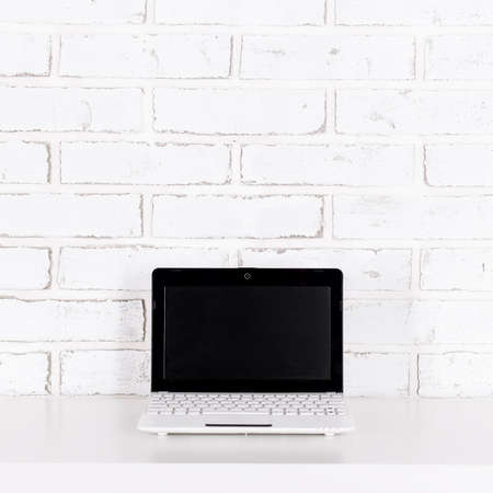 modern laptop with blank screen on the table over white brick wall backgroundの写真素材