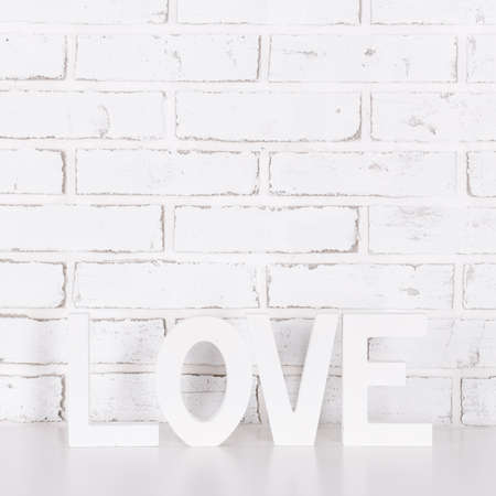 wooden word love over white brick wall backgroundの写真素材