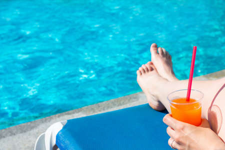 summer, travel and vacation background - woman sitting with alcohol cocktail near swimming poolの写真素材