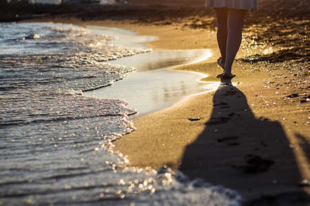 Beach travel concept - woman walking on sandy beach leaving footprints in the sandの写真素材