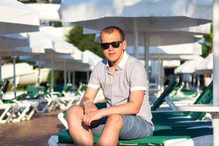 summer concept - young handsome man sitting under umbrellaの写真素材