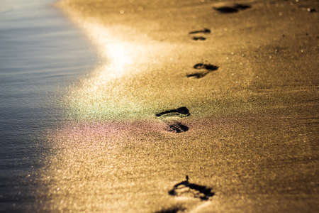 Beach travel concept - close up of footprints on the sunset beachの写真素材