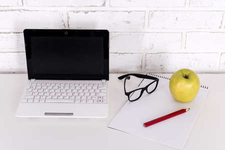 workplace at home or in office - white modern laptop, glasses and notebook on the table