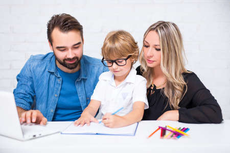 happy family with cute little school boy doing homework togetherの写真素材
