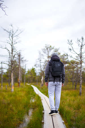 travel concept - rear view of man hiking in autumn forestの写真素材