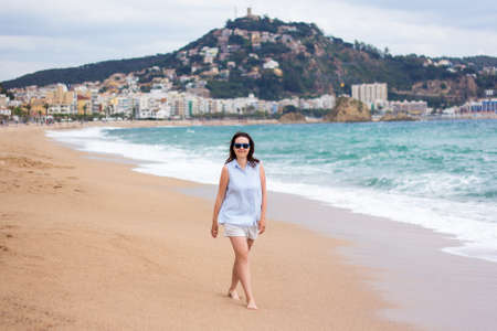 beach travel - young woman walking on sandy beach in Blanes, Spainの写真素材
