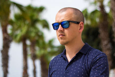 portrait of young man in summer park with palm treesの写真素材