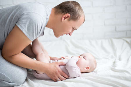 happy young father playing with cute baby girl at homeの写真素材