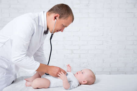 side view of doctor pediatrician examining little baby patient in hospital