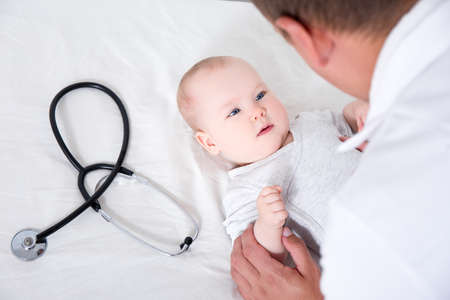 pediatry concept - close up of male doctor pediatrician examining little baby patient in clinic