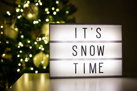 winter and first snow concept - lihtbox with text it's snow time in dark room with decorated christmas treeの写真素材