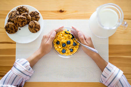 healthy breakfast concept - top view of kitchen table with milk, cookies and corn flakes with...