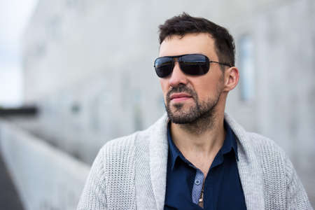 close up portrait of handsome business man in sunglasses over modern building
