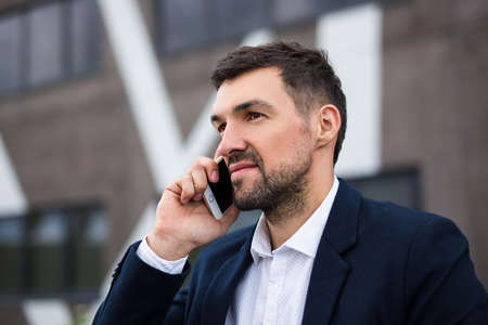 close up portrait of handsome man talking by phone over modern building background