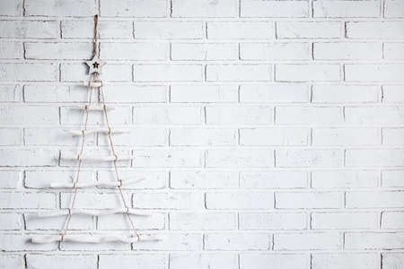wooden chrtistmas tree decoration over white brick wall background with copy space