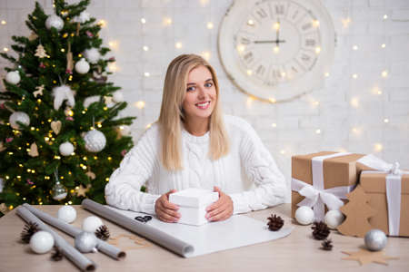 young woman packing Christmas gifts in living roomの写真素材