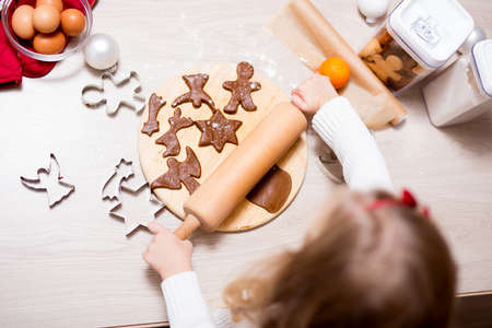 top view of little girl making Christmas cookies or gingerbreads in kitchenの写真素材