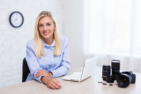 young woman professional photographer with camera, computer and photography equipment working in modern officeの写真素材
