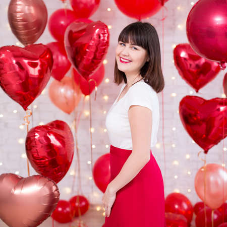 valentine's day concept - cheerful beautiful woman posing with red heart-shaped balloonsの写真素材