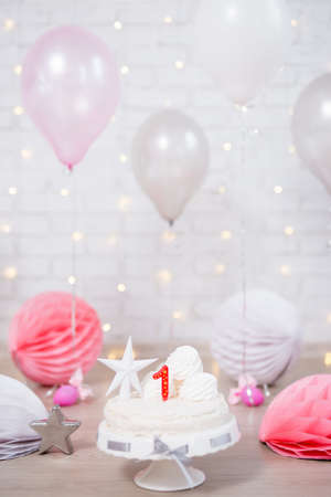 first birthday background - beautiful cake with one candle and balloons over white brick wallの写真素材