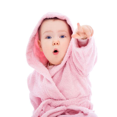 cute baby girl in pink bathrobe pointing at something isolated on white backgroundの写真素材
